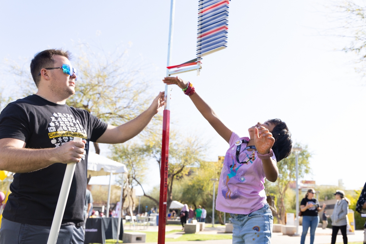 A young girl jumps up to smack at a pole that measures the height of your jump