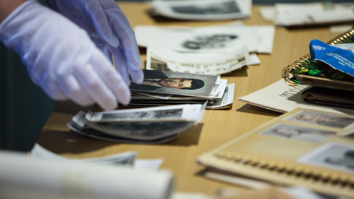 Hands with gloves handling archive materials.