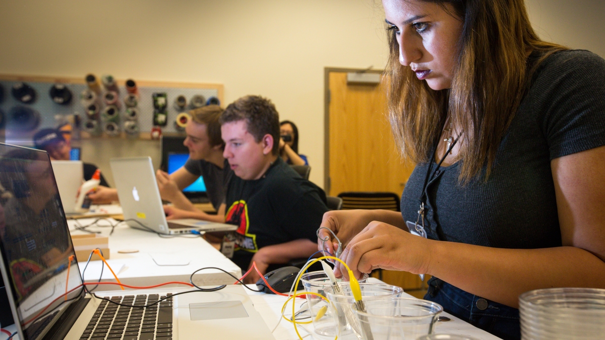 group of students watching instructor construct small electronic instrument
