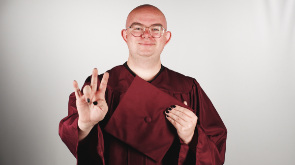 ASU student in graduation regalia holding up a pitchfork.