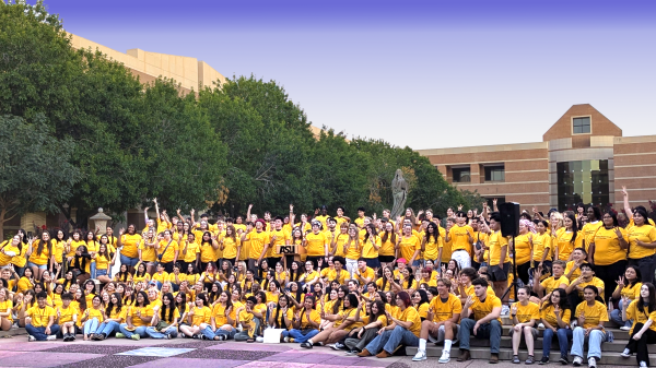 Large group of students wearing gold T-shirts pose for a group photo.