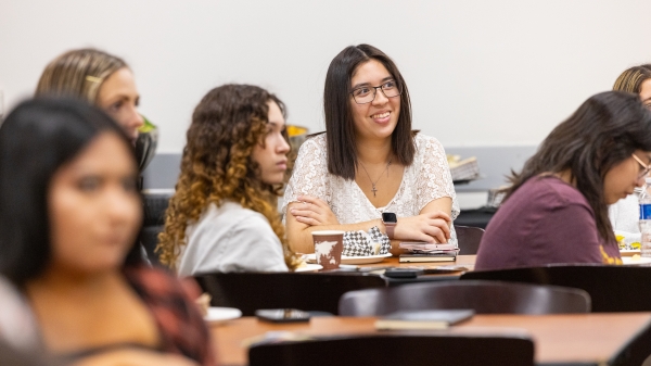 Student wearing white is smiling towards something in the room