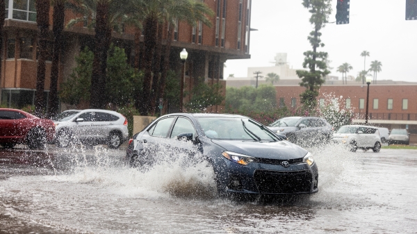 Cars drive through a partially flooded intersection in Tempe, Arizona