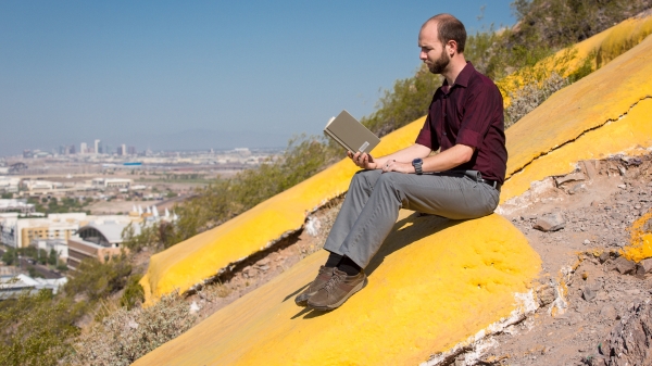 man reading book on mountain