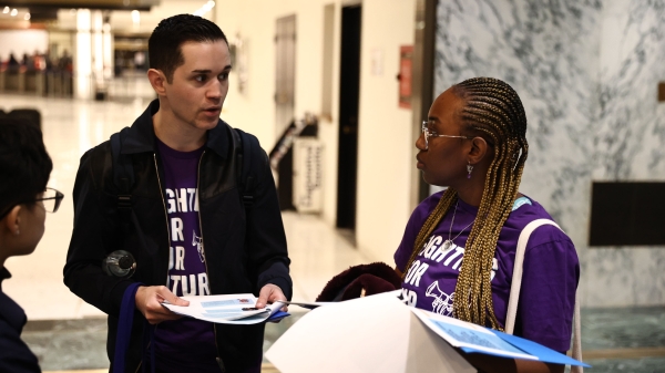 ASU alum Jake Martinez holding a packet of papers and talking to someone.