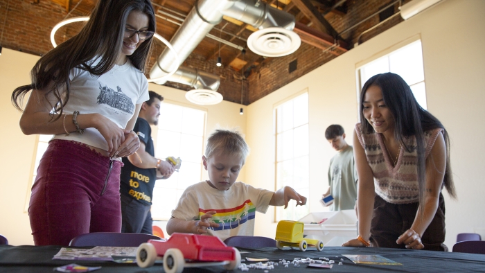Cameryn Franklin and Jessica Marencic assist a child at a craft table.