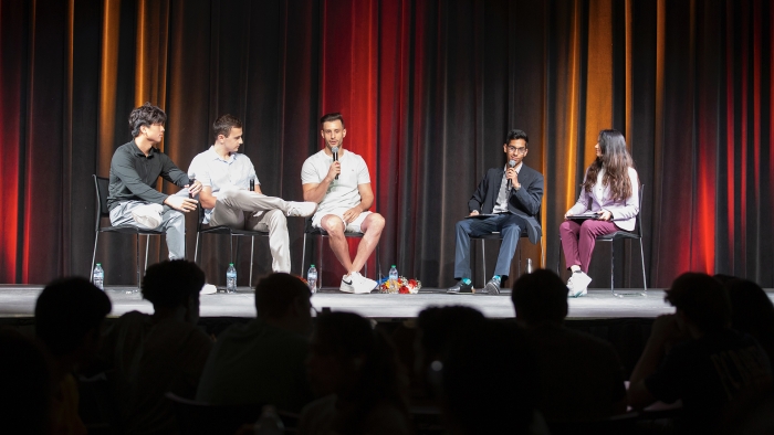 Students and industry experts speak on stage at a panel.