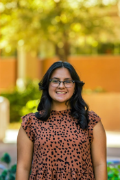 Diane Banuelos in brown shirt with black spots standing outside smiling at the camera